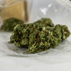 Detailed view of cannabis buds in clear plastic showing trichomes and green hues.