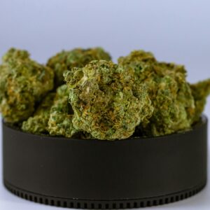High-quality close-up image of cannabis buds in a black container, showcasing their texture and detail.